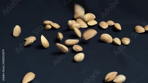 Almonds are poured onto a black background