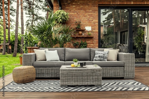 An outdoor terrace with wooden floor and rattan furniture in the garden.