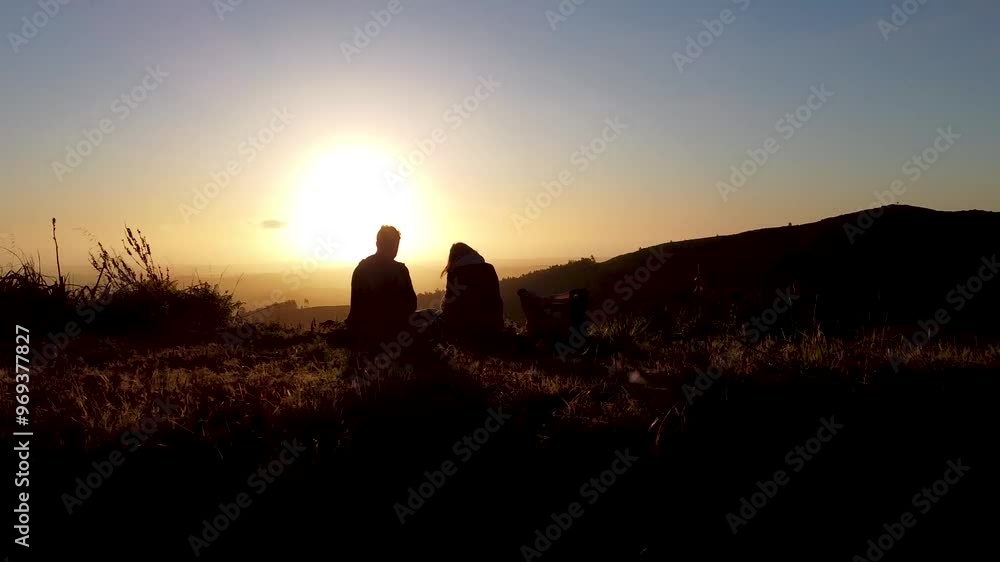 Drone flight captures silhouettes of a couple romantically watching the sunset. Drone flight captures silhouettes of a couple romantically watching the sunset.