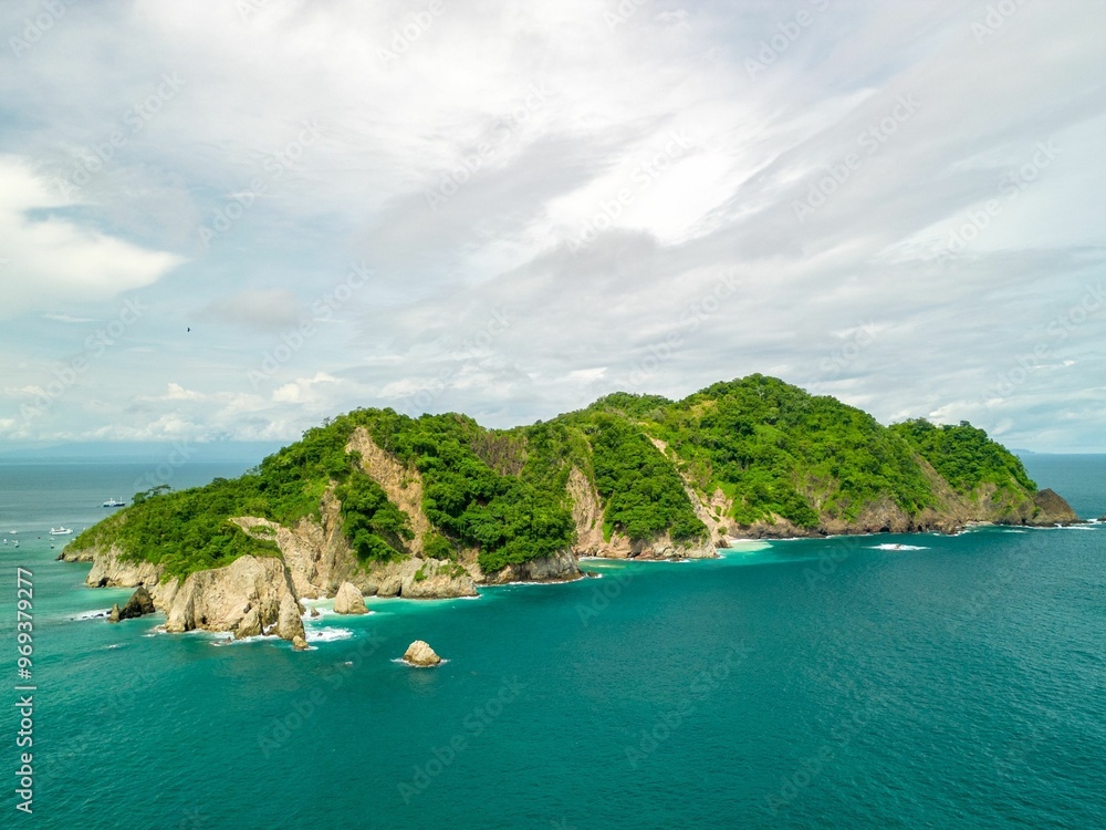 Fototapeta premium Aerial view of a lush green island with turquoise waters.