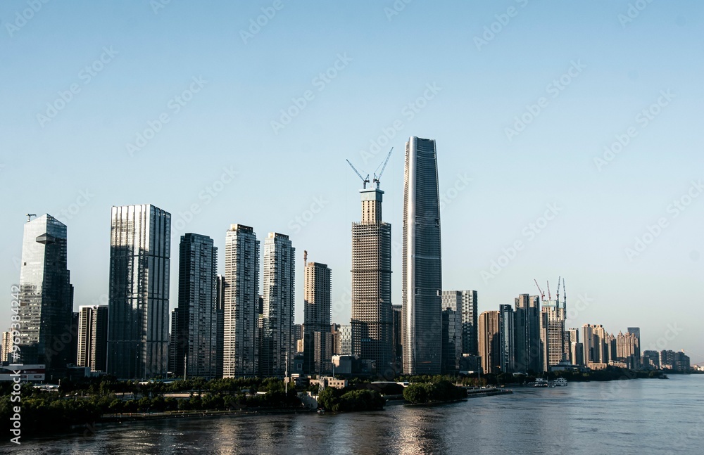 Fototapeta premium Of modern skyscrapers along a river in a city during daytime.