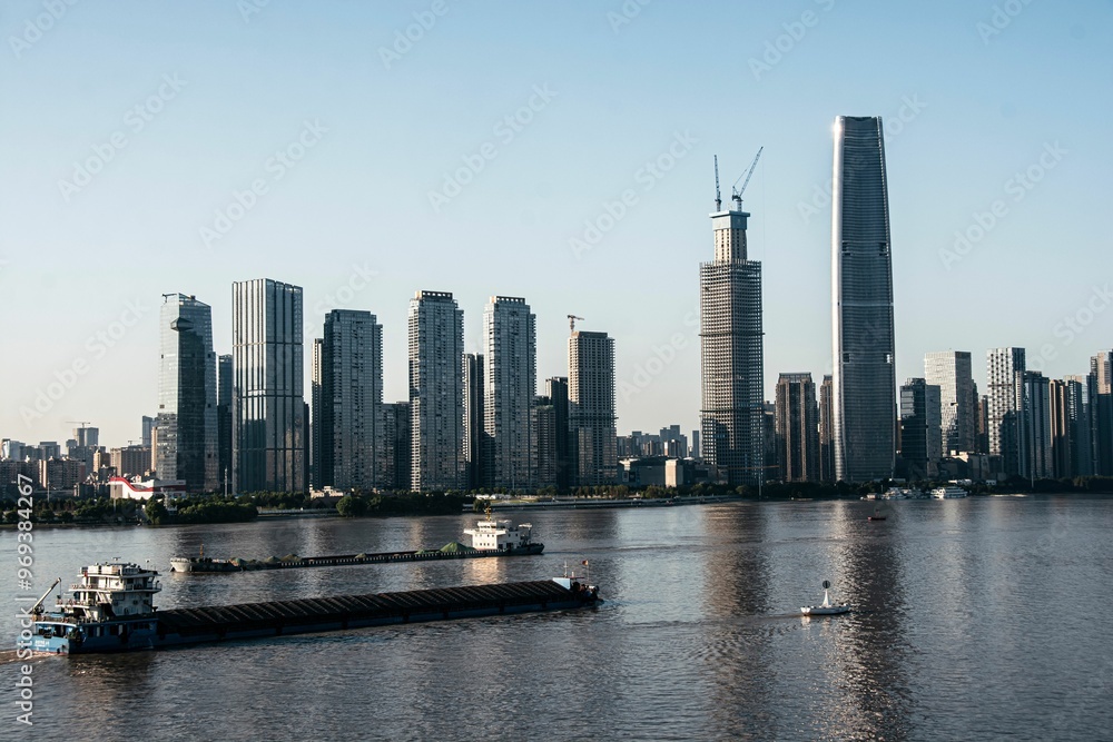 Obraz premium Modern cityscape with skyscrapers and river cargo ships.