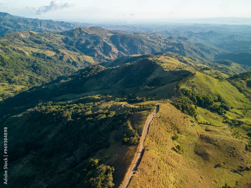 View of rolling green hills and mountains under a clear blue sky in Cerro Pinocho, Monteverde