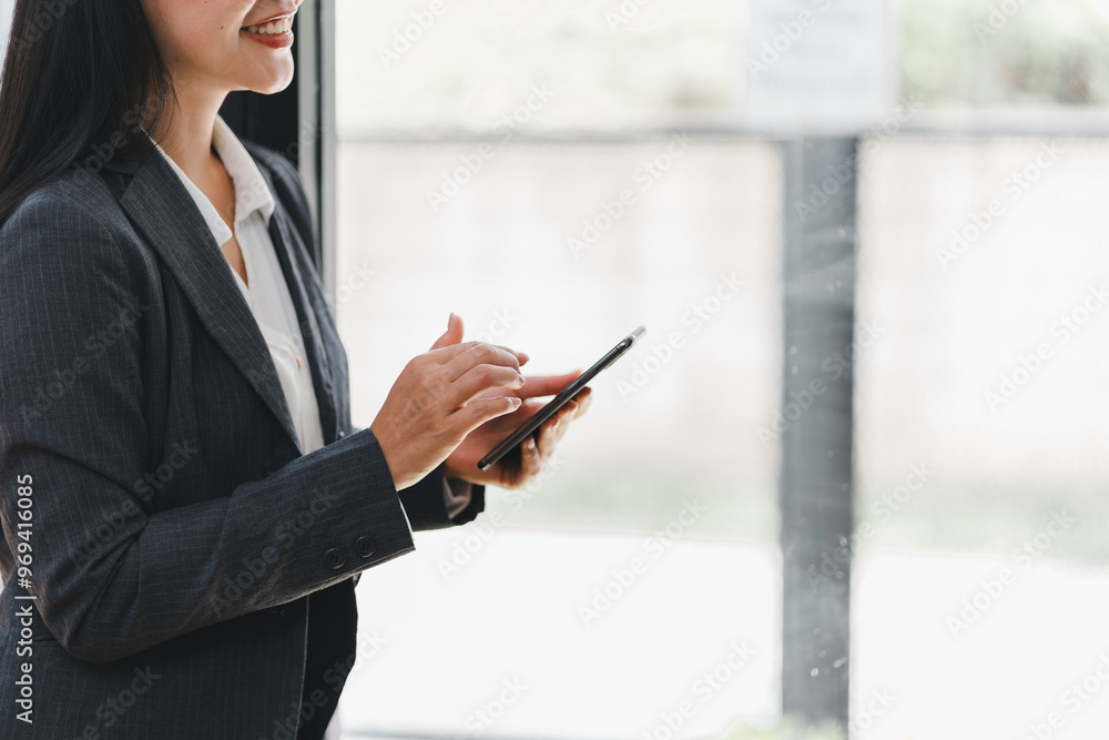 A professional woman in suit smiles while using her smartphone, showcasing confidence and engagement A professional woman in suit smiles while using her smartphone, showcasing confidence and engagement