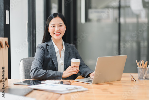 Professional woman smiling with coffee at modern office desk