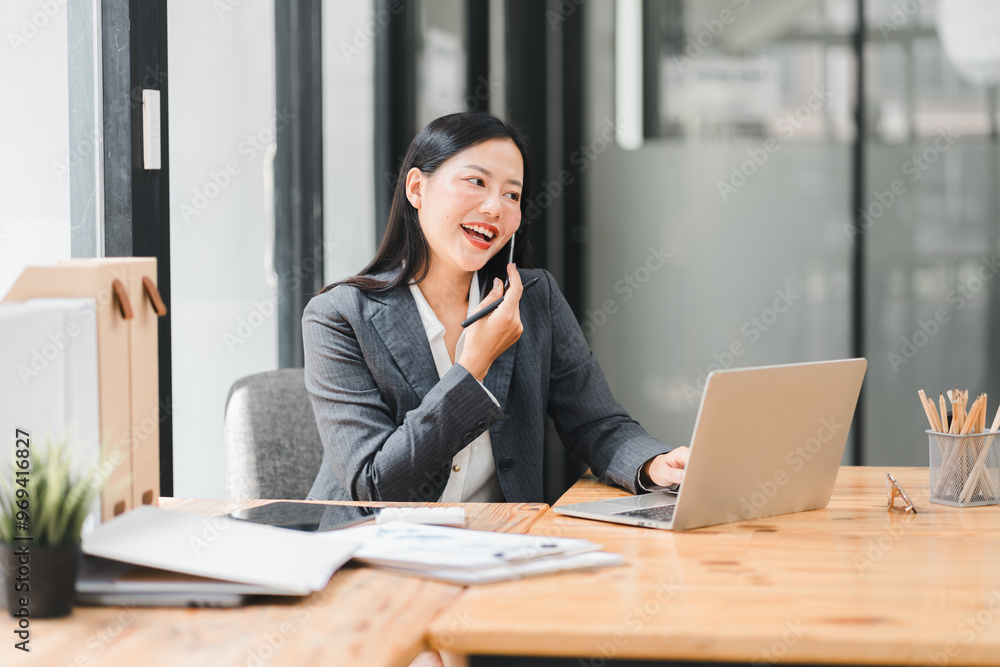 A professional woman is engaged in phone call while working on her laptop A professional woman is engaged in phone call while working on her laptop