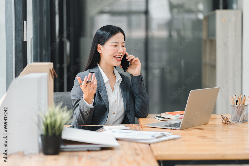 A professional woman engaged in phone conversation at her office desk, exuding confidence and focus A professional woman engaged in phone conversation at her office desk, exuding confidence and focus
