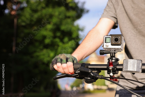 Man riding bicycle with modern action camera outdoors, closeup