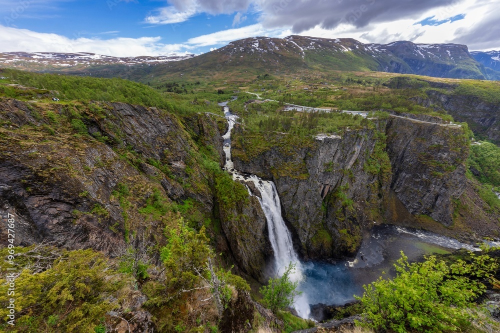 Stunning view of Voringsfossen waterfall cascading into a gorge surrounded by greenery and mountains Stunning view of Voringsfossen waterfall cascading into a gorge surrounded by greenery and mountains