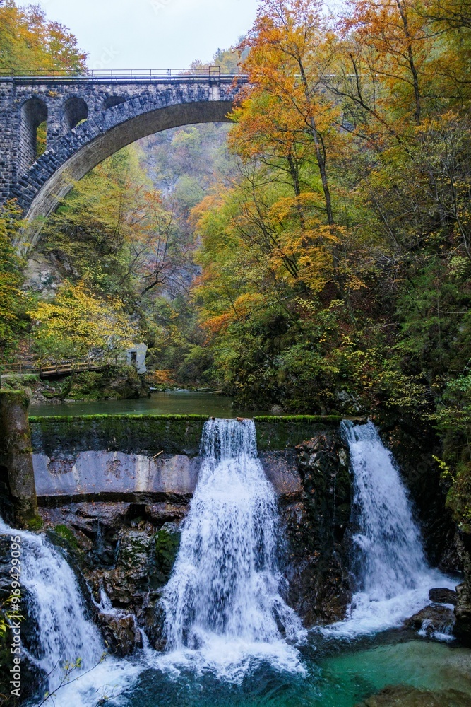Stone arch bridge over waterfall in autumn forest Stone arch bridge over waterfall in autumn forest
