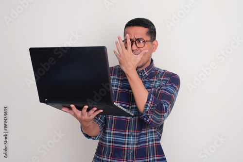 A man showing scared expression when looking at his laptop photo