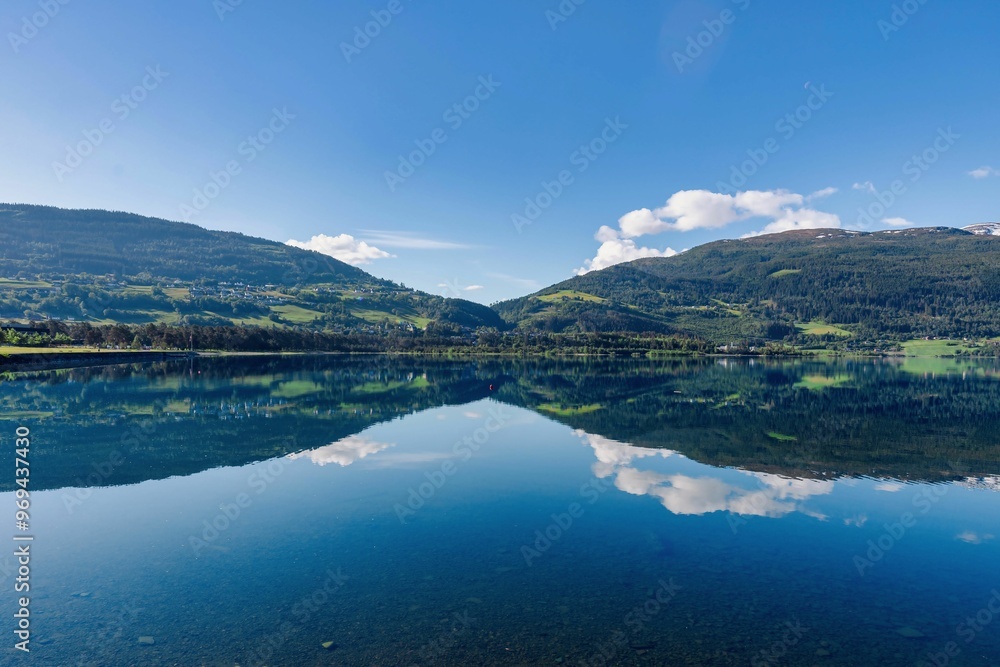 Serene landscape of a lake reflecting surrounding mountains and a clear blue sky in Norway Serene landscape of a lake reflecting surrounding mountains and a clear blue sky in Norway
