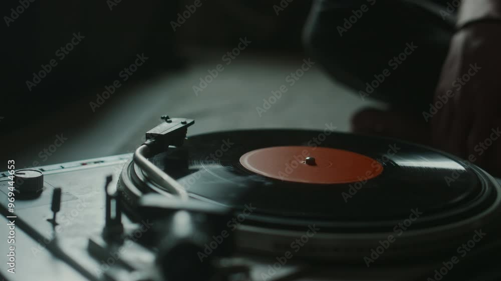 Close-up view of unknown young man putting on vinyl record and turning on player in dim light Close-up view of unknown young man putting on vinyl record and turning on player in dim light