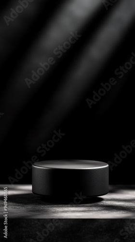 Minimalistic black pedestal illuminated by dramatic lighting on a dark background, perfect for showcasing products or artwork.
