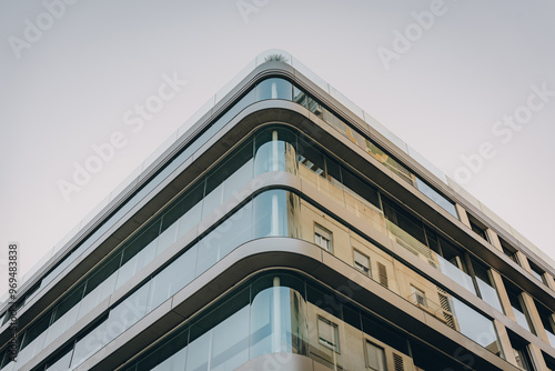 Glass-walled office building with rounded edges, featuring contemporary architectural style in an urban area.
