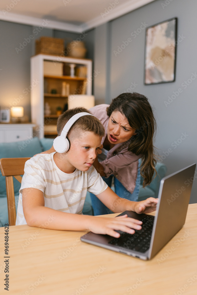 Frustrated Mother Reacts to Son Focused on Laptop with Headphones Frustrated Mother Reacts to Son Focused on Laptop with Headphones