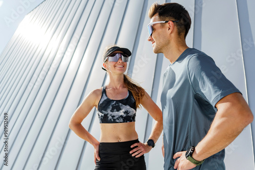 Foto Two fit athletes standing confidently after a successful workout, smiling under the bright sunlight