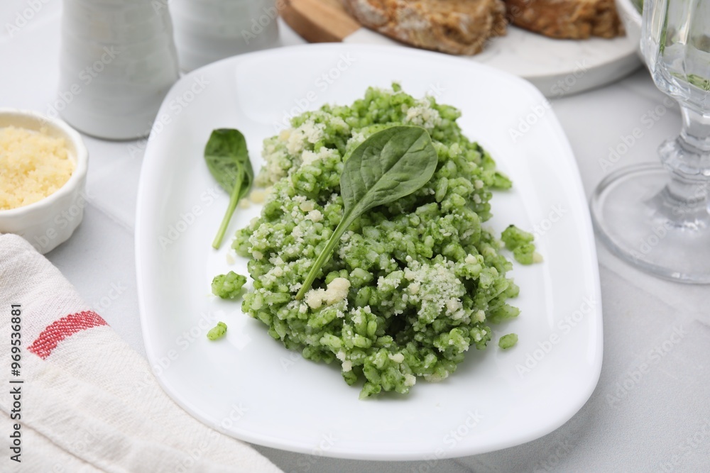 Delicious spinach risotto with parmesan cheese on white tiled table, closeup Delicious spinach risotto with parmesan cheese on white tiled table, closeup