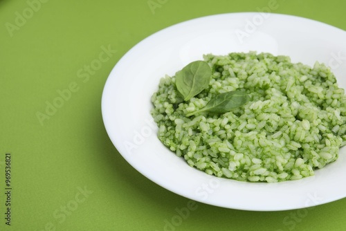 Delicious spinach risotto on light green background, closeup