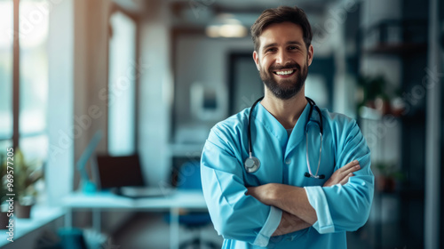 A smiling doctor, wearing a blue coat and a stethoscope around his neck, poses with his arms crossed in a modern medical office. The background shows a medical office environment 