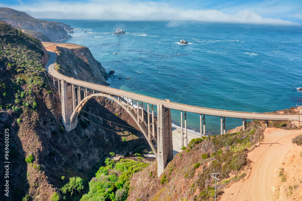 Fototapeta premium Beautiful scenery of Pacific Ocean coast along Highway 1 and Big Sur, wonderful aerial view of Bixby Bridge, sunset, sunrise, fog. Concept, travel, vacation, weekend
