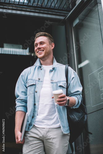 Positive male taking coffee going out of coffee shop