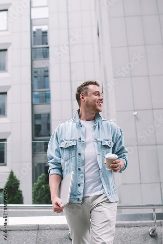 Excited male drinking coffee walking in modern district