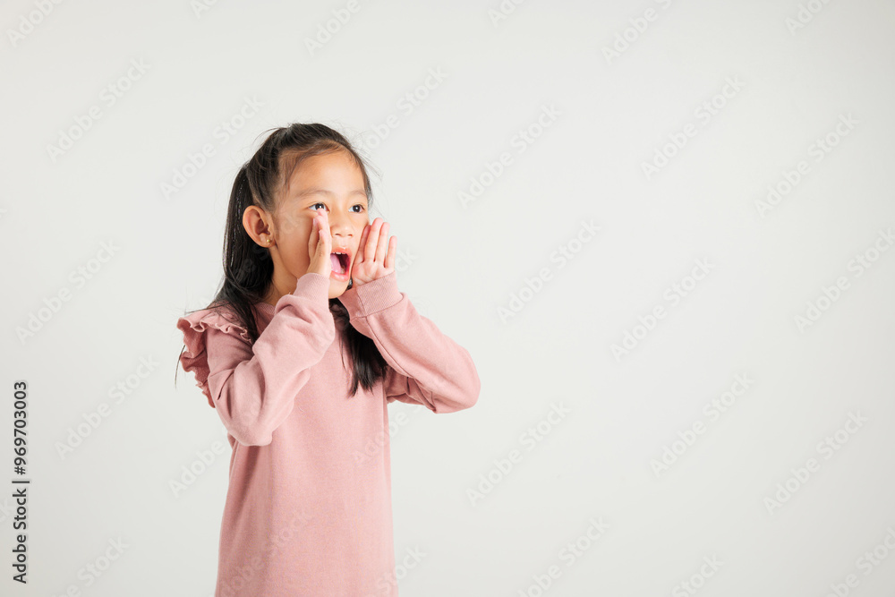 Asian happy portrait cute young kid girl standing hand on mouth talking news announcement studio shot isolated on white background, Thai kindergarten child announcement Asian happy portrait cute young kid girl standing hand on mouth talking news announcement studio shot isolated on white background, Thai kindergarten child announcement