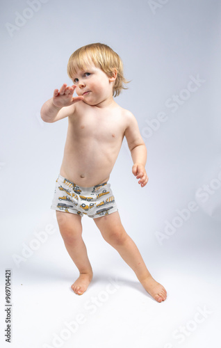 A young toddler plays on a white backdrop in a photo studio.