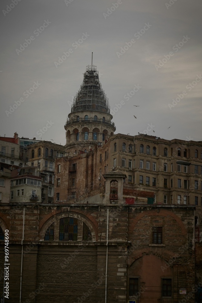 Obraz premium View of Galata Tower in Istanbul, Turkey, with surrounding historic buildings and a cloudy sky