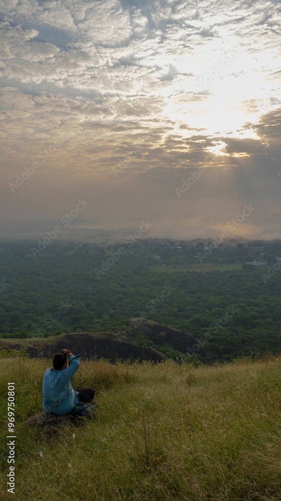 Photographer capturing a scenic sunset from a hilltop. Photographer capturing a scenic sunset from a hilltop.