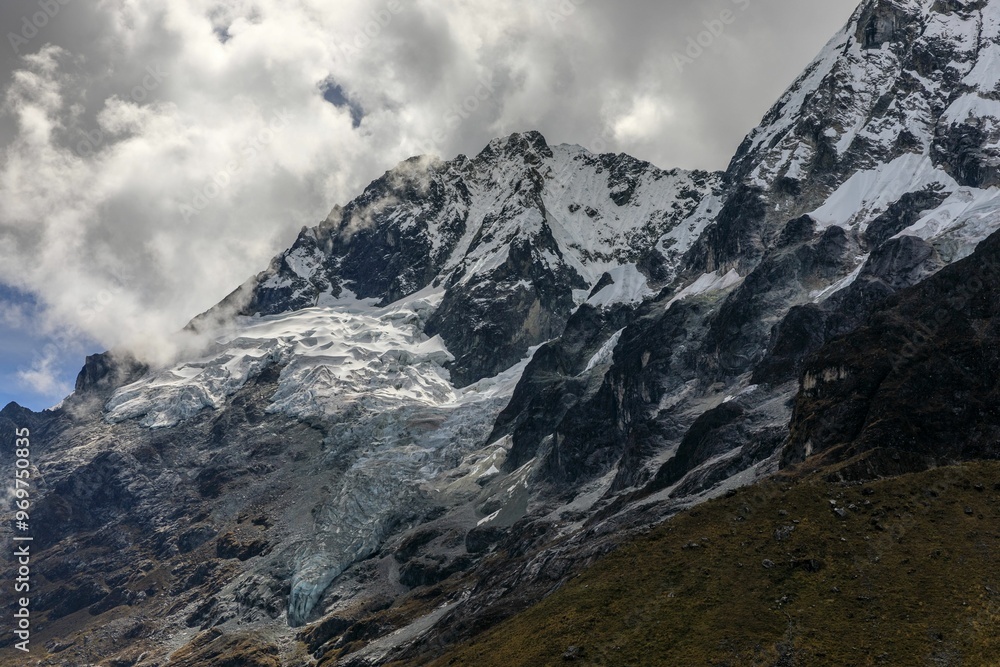 Stunning view of the snow-capped Salkantay Mountain peak with clouds against a clear blue sky. Stunning view of the snow-capped Salkantay Mountain peak with clouds against a clear blue sky.