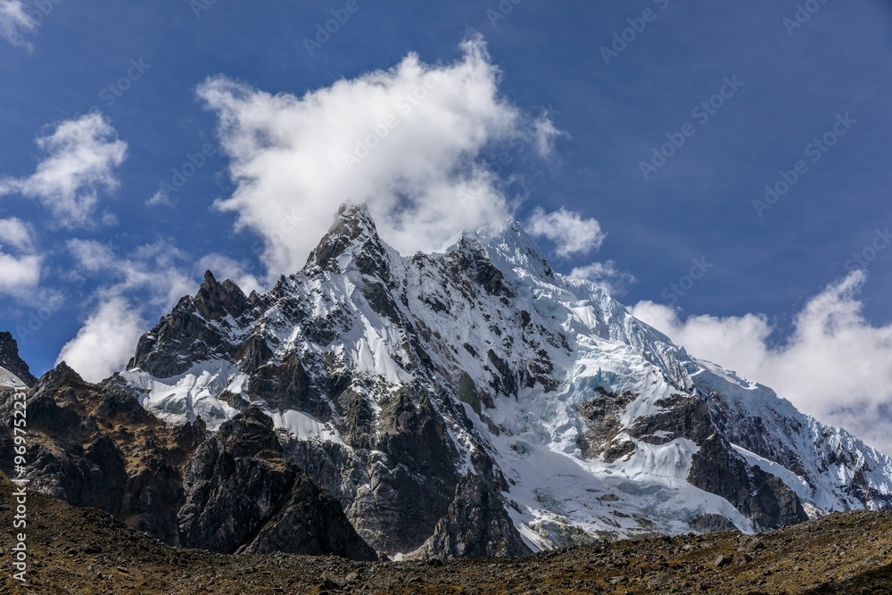 Stunning view of the snow-capped Salkantay Mountain peak with clouds against a clear blue sky. Stunning view of the snow-capped Salkantay Mountain peak with clouds against a clear blue sky.