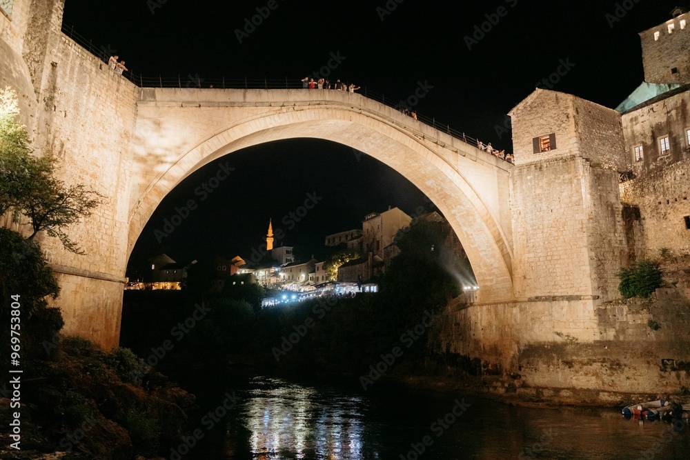 Obraz premium Stari Most bridge in Mostar, Bosnia and Herzegovina, with illuminated buildings in the background