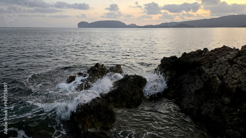 the sea waves crash on the rocks at sunset in the bay of Porto Conte
