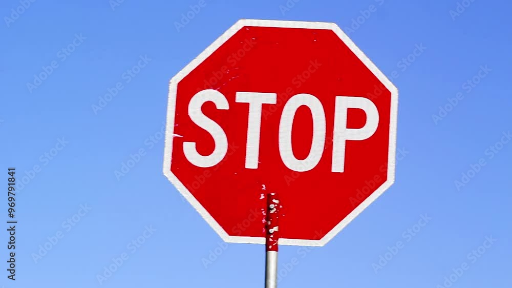 Stop sign rocking back and forth against blue sky Stop sign rocking back and forth against blue sky