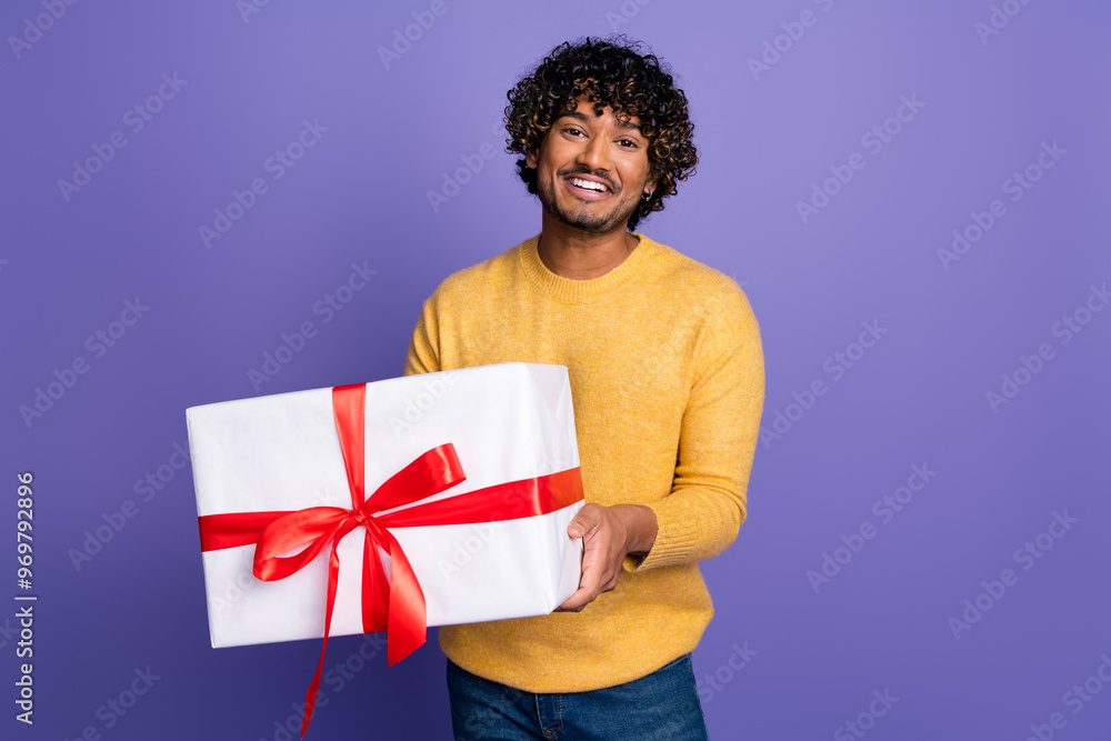 Photo of cheerful nice man wear trendy yellow clothes hold gift isolated on purple color background Photo of cheerful nice man wear trendy yellow clothes hold gift isolated on purple color background