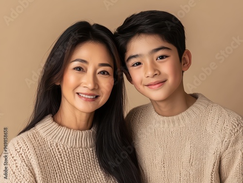 Portrait of a happy Asian mother and son wearing sweaters in a studio against a beige background for a commercial advertising design