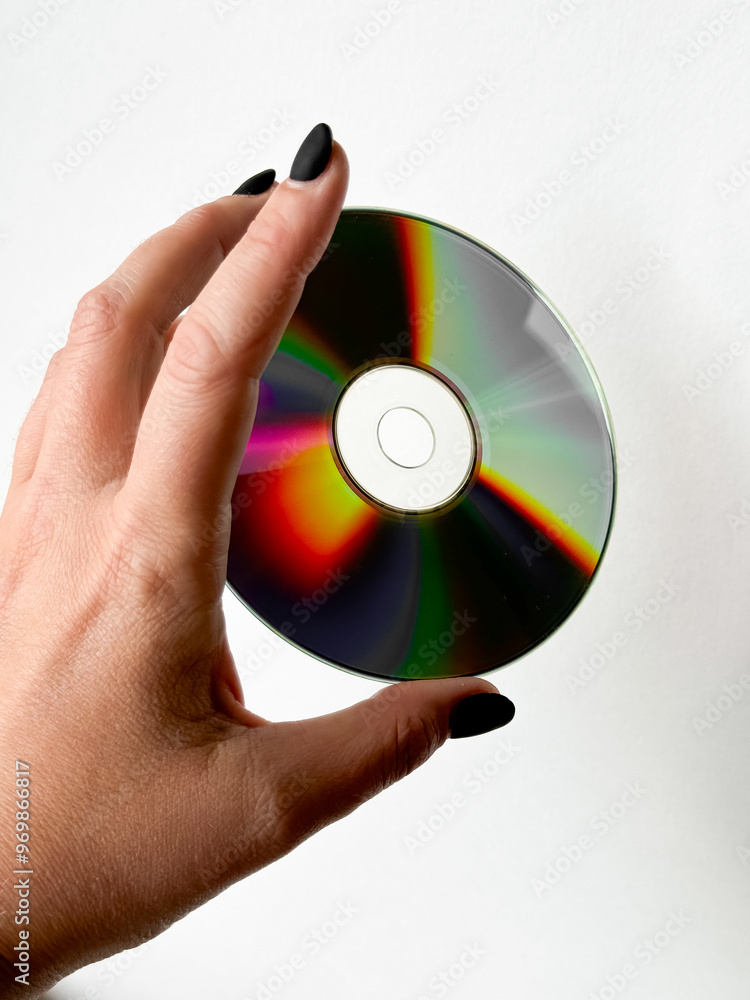 Hand holding reflective cd against white background with black nails Hand holding reflective cd against white background with black nails