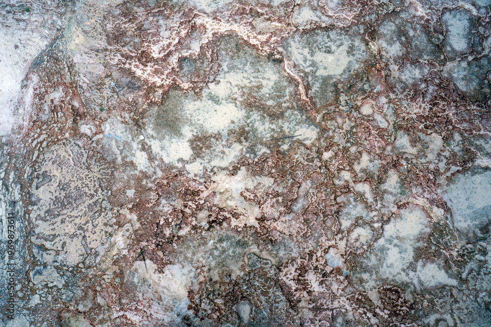 A close-up of Pamukkale's geological formations, showcasing intricate patterns of red-tinged mineral deposits amidst white calcium carbonate.