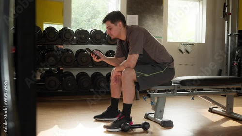 Man Checking His Phone During a Workout in the Gym. A Casual Moment During Gym Training.