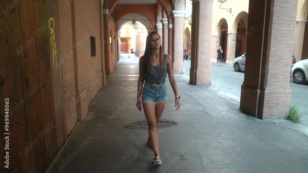 A woman leisurely walking through a historic and beautiful archway in Bologna, Italy A woman leisurely walking through a historic and beautiful archway in Bologna, Italy