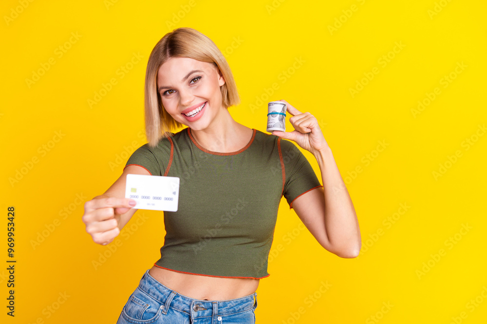 Photo of successful girl with bob hairdo dressed khaki crop top hold credit card show you dollars isolated on yellow color background Photo of successful girl with bob hairdo dressed khaki crop top hold credit card show you dollars isolated on yellow color background
