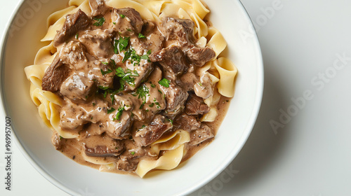 A delicious bowl of creamy beef stroganoff served atop wide egg noodles, garnished with fresh parsley. photo