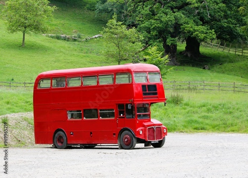 Obraz na plátně A red retro double-decker tourist bus in the parking lot of a green and beautifu