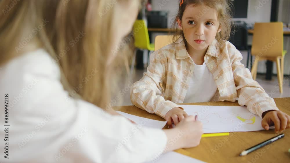 A vibrant and lively classroom environment where enthusiastic children are engaged in drawing and learning collaboratively at a large table A vibrant and lively classroom environment where enthusiastic children are engaged in drawing and learning collaboratively at a large table