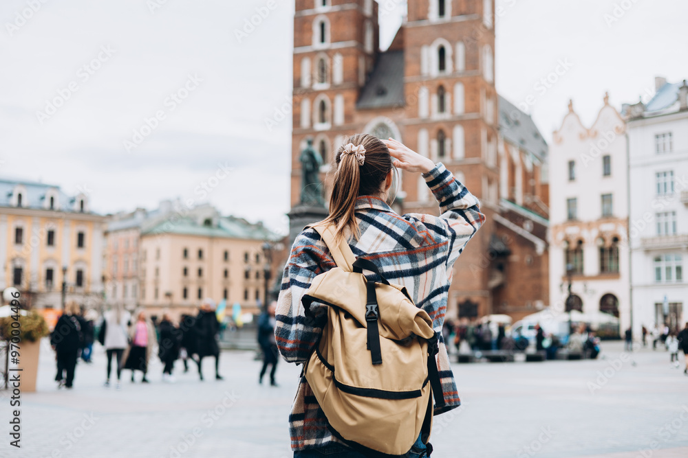 Tourist happy woman posing on Market Square in Krakow, Traveling Europe in autumn. St. Marys Basilica, no face, rear view Tourist happy woman posing on Market Square in Krakow, Traveling Europe in autumn. St. Marys Basilica, no face, rear view