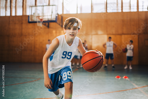 Billede på lærred Active young player dribbling basketball in gym