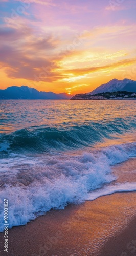 Golden sunset over calm waves at a beach with distant hills in the background