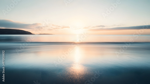 A serene ocean view from a secluded beach with the sun rising over the calm water and creating a soft golden reflection.